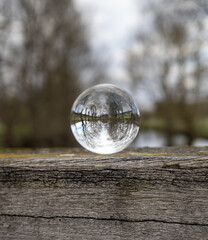 Crystal lens on wooden beam and landscape