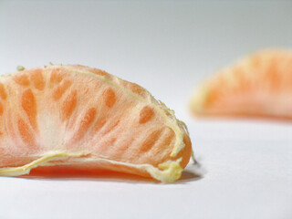 two pieces of peeled mandarines on neutral bakcground