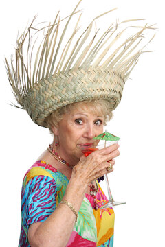 A beautiful senior woman on vacation sipping a tropical cocktail.  Isolated
