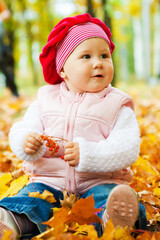 Baby girl sitting in autumn leaves