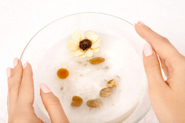 The top view - hands hold a bath with a flower and salt