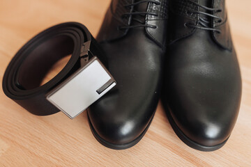 Men's shoes and belt. Elegant black men's leather shoes and belt on a brown background. Men's style. Fashion. Business