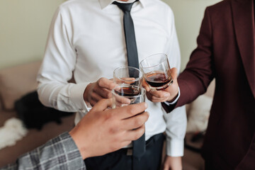 Cropped photo. Men hold glasses of whiskey and clink glasses. Beautiful male hands. Business style. Alcohol