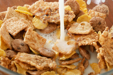 Milk pouring onto corn flakes bowl.