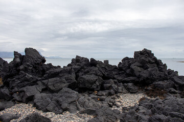 Fototapeta na wymiar A rocky shore of South Iceland beach with black volcanic rocks in the Iceland South coast