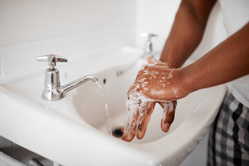 Clean, hygiene and person washing hands in the bathroom with soap for wellness, health and bacteria prevention. Protection, home and man cleaning hand with water in his apartment as morning routine