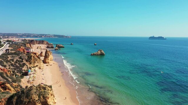 Portuguese southern beaches in aerial video city Portimao beach tres castelos. tourist cruise ship at sea in the background.