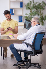 Fototapeta premium Young male patient visiting old male doctor radiologist