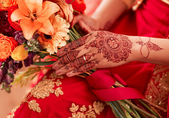 Fototapeta na wymiar Henna, hands and Indian woman at her wedding event with flowers or bouquet for decoration or design. Luxury, marriage and traditional culture by a bride with art pattern on her hand for celebration