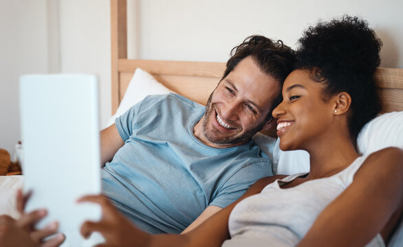 Happy couple, smile and relax on bed for selfie, photo or morning post together at home. Interracial man and woman person smiling for fun profile picture, memory or vlog in bedroom at the house