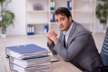 Fototapeta premium Young male employee and too much work in the office