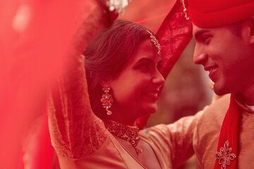 Wedding, marriage and red veil with couple together in celebration of love at a ceremony. Happy, romance or islamic with a hindu bride and groom getting married outdoor in tradition of their culture