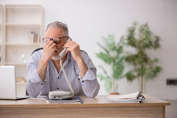 Old male employee working in the office
