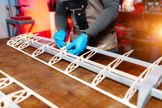 Close-up image of young male engineer or technician working on drone details in lab. Plane wing.