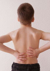 Fototapeta na wymiar naked back of boy, child 8-10 years old grabbed a sore spot, curved spine, pain in spine, concept of therapeutic massage for osteochondrosis, scoliosis, back pain, intervertebral hernia