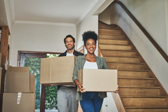 Happy couple, real estate and moving in new home with boxes for renovation, investment or relocation. Interracial man and woman owner carrying box for property rent, mortgage loan or move together