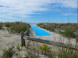 Blue mat on sand path to beach between sand dunes