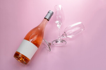 Wine bottle mockup, unopened bottle of rose wine and two glasses on pink background, top view, copy space, flat lay