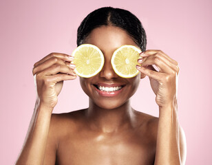 Happy woman, beauty and eyes with lemon in studio, pink background and vitamin c benefits. Face, african model and fun with citrus fruits for natural skincare, vegan cosmetics and facial aesthetic