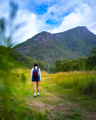 Naklejka premium beautiful girl with backpack hiking in mount barney national park, queensland, australia; large mighty mountains near brisbane and gold coast