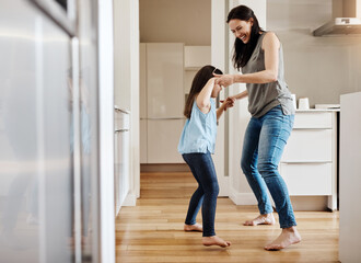 Holding hands, dance and a child with a mother in the kitchen, bonding and quality time together. Smile, laughing and a mom teaching her daughter with dancing, love and happiness with fun in a house