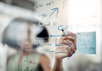 Obraz premium Glass wall, hands and business woman writing, strategy or planning in office. Brainstorming, board and female person write ideas, working on project and schedule, mindmap or information in workplace.