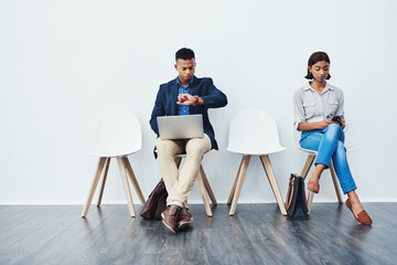 Phone, laptop and people in waiting room for an internship search the internet, web or website sitting on chairs. Interview, work and young employees texting and typing online ready for a new job