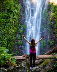 long haired hiker girl standing in frong of large tropical waterfall in lamington rainforest, queensland, australia; famous larapinta falls hidden deep in the jungle