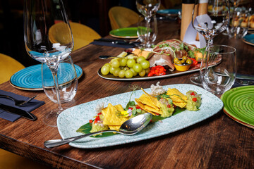 Guacamole with corn nachos on a plate in a restaurant.