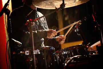 Close-up of drummer drumsticks with a drum set.