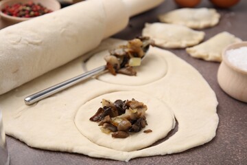 Process of making dumplings (varenyky) with mushrooms. Raw dough and ingredients on grey table, closeup