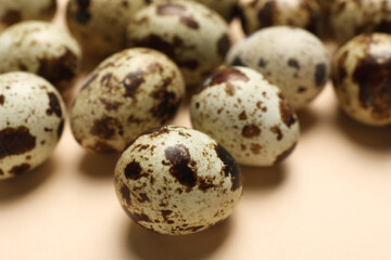 Many speckled quail eggs on beige background, closeup
