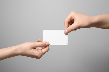Obraz premium Women holding blank gift card on light grey background, closeup