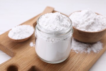Jar and spoon of starch on wooden board, closeup
