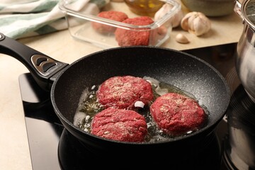 Cooking vegan cutlets in frying pan on stove, closeup