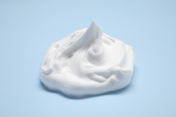 Sample of shaving foam on light blue background, closeup