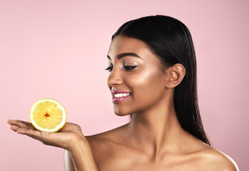Skincare, face and smile of woman with an orange in studio isolated on pink background. Fruit, natural cosmetics and Indian female model holding food for healthy diet, nutrition or vitamin c to detox