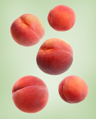 Fresh ripe peaches falling on pale olive background