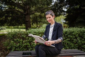 Fototapeta premium mature pensioner senior woman caucasian female read newspaper outdoor