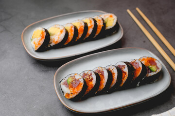 Close up spicy tuna sushi roll on the stone table top. Japanese food and sushi concept.