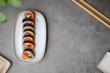 Top view of sushi rolls of tuna, cucumber, and avocado with copy space of the black concrete table.