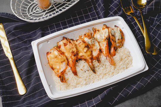 grilled tiger shrimp over rice in a togo box. Online food delivery concept.