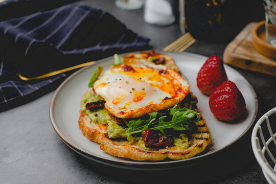 healthy breakfast and eating. Sourdough toast with avocado, arugula, and fried eggs.