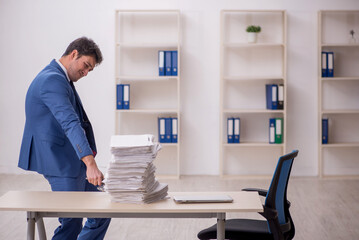 Young male employee unhappy with excessive work in the office