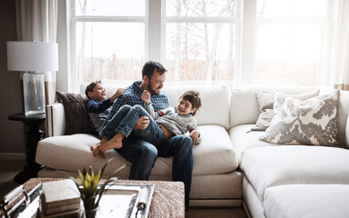 Father, boy children at family home and playing in living room, fun and carefree with love, energy and happiness. Man play with kids on sofa, crazy and playful with laughter and joy in the house