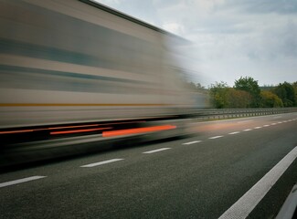 A truck driving on the highway at dusk. Motion blur on the highway. Evening shot of a truck....