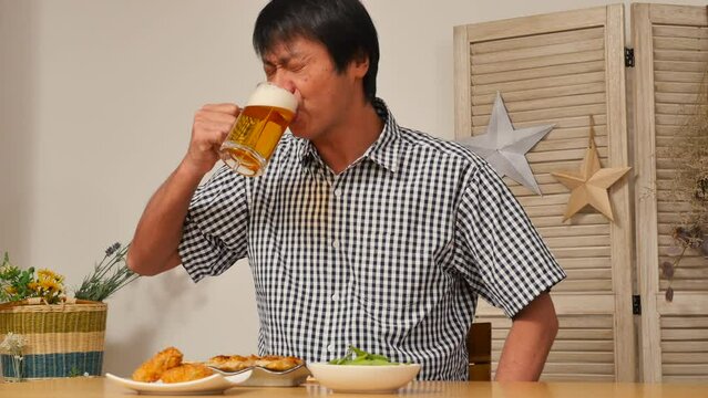 自宅で一人で晩酌をする中年男性