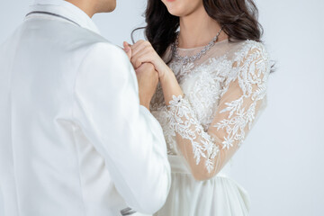 Bride and groom holding hands together in romantic moment. Couple in wedding or pre wedding at studio concept. Couple posing in studio shot for wedding and engagement ceremony with white background.