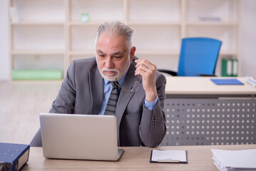 Old male employee working in the office