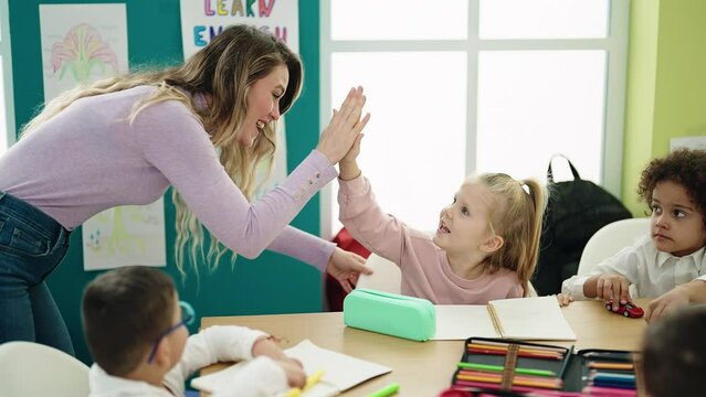 Woman and group of kids having lesson high five at classroom